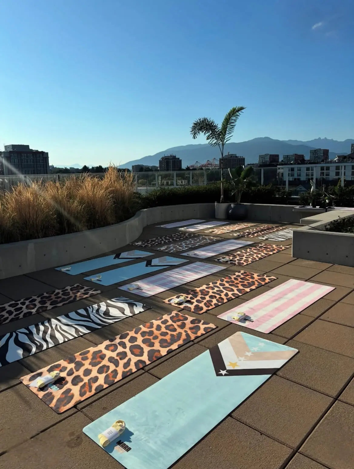Collection of aesthetic patterned yoga mats on a rooftop with cityscape in the background