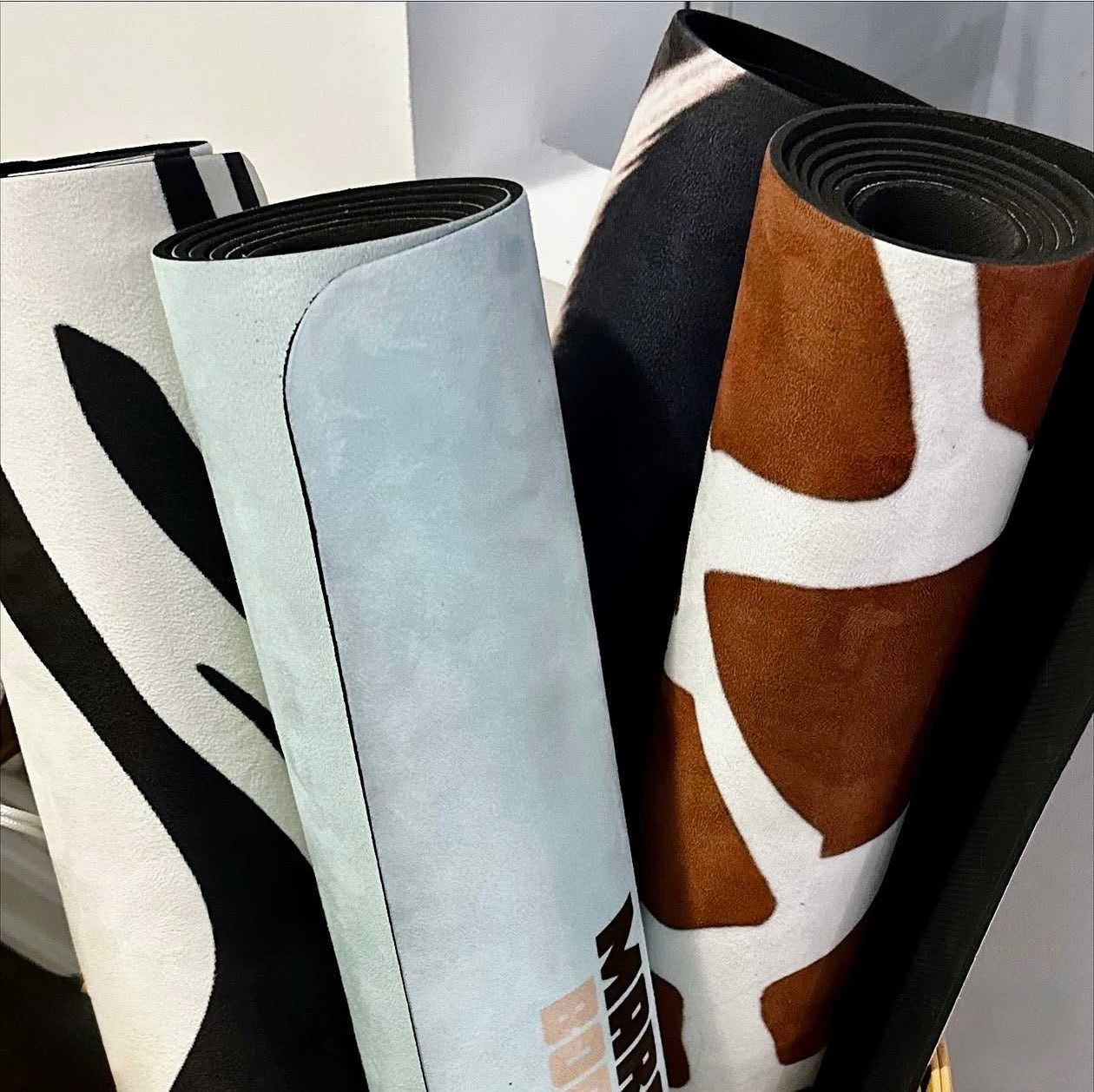 four rolled aesthetic animal print yoga mats, giraffe print yoga mat, ebra print yoga mat, cowhide orint yoga mat and blue hot yoga mat