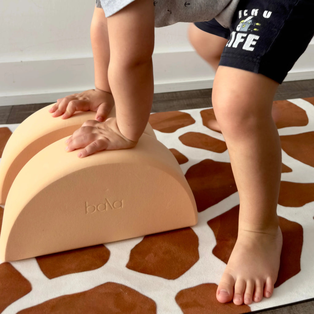 Children's feet on a brown giraffe spots pattern sustainable yoga mat