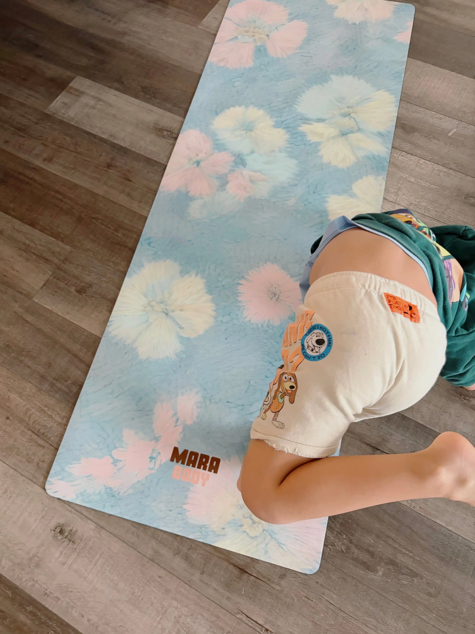 flower motif blue yoga mat on a floor with a child in a yoga pose