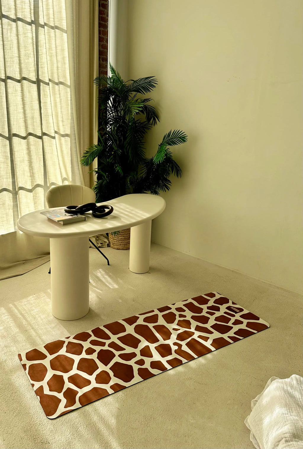 Giraffe patterned rug on a light-colored floor with a white table and plant in the background.