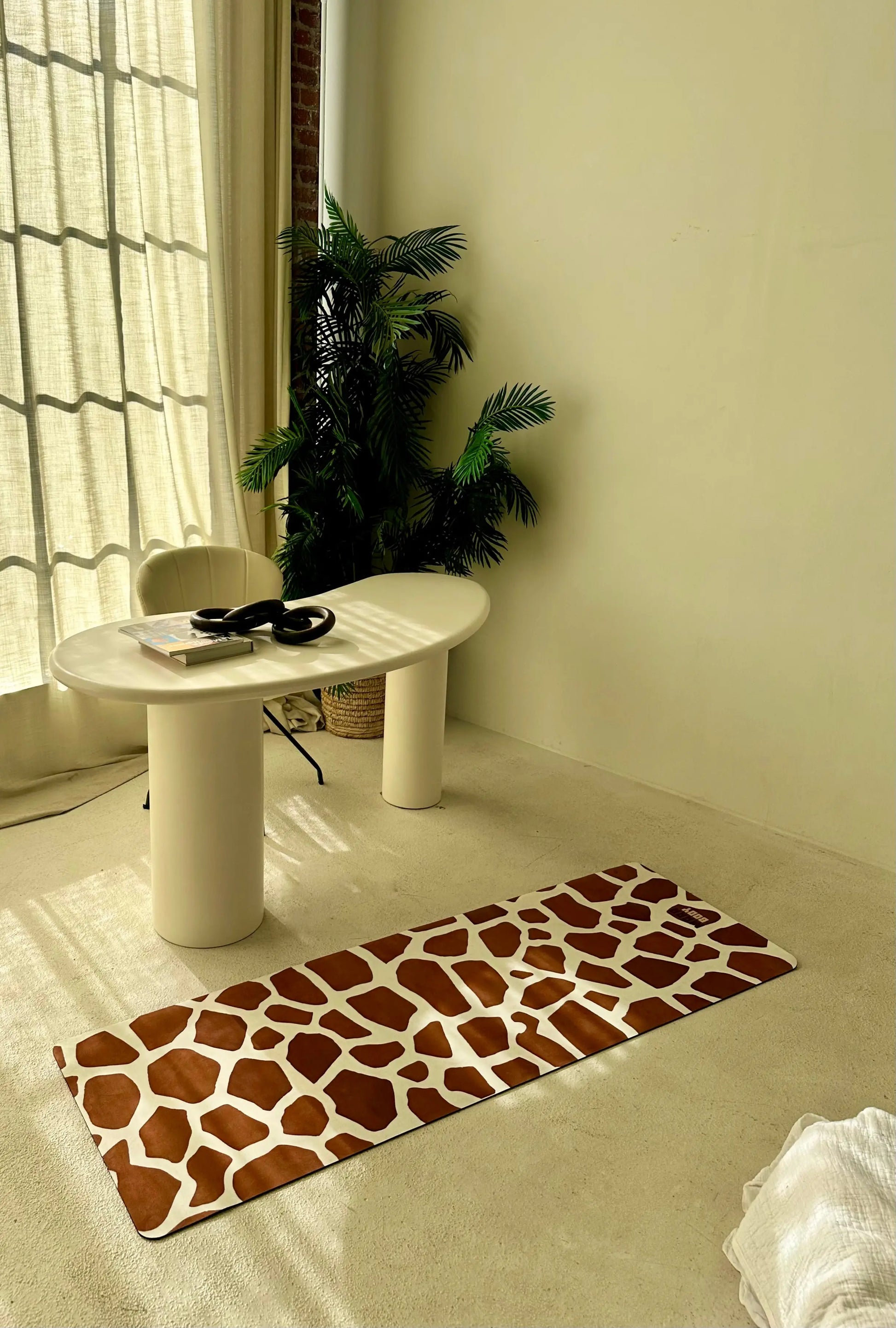 Giraffe patterned rug on a light-colored floor with a white table and plant in the background.