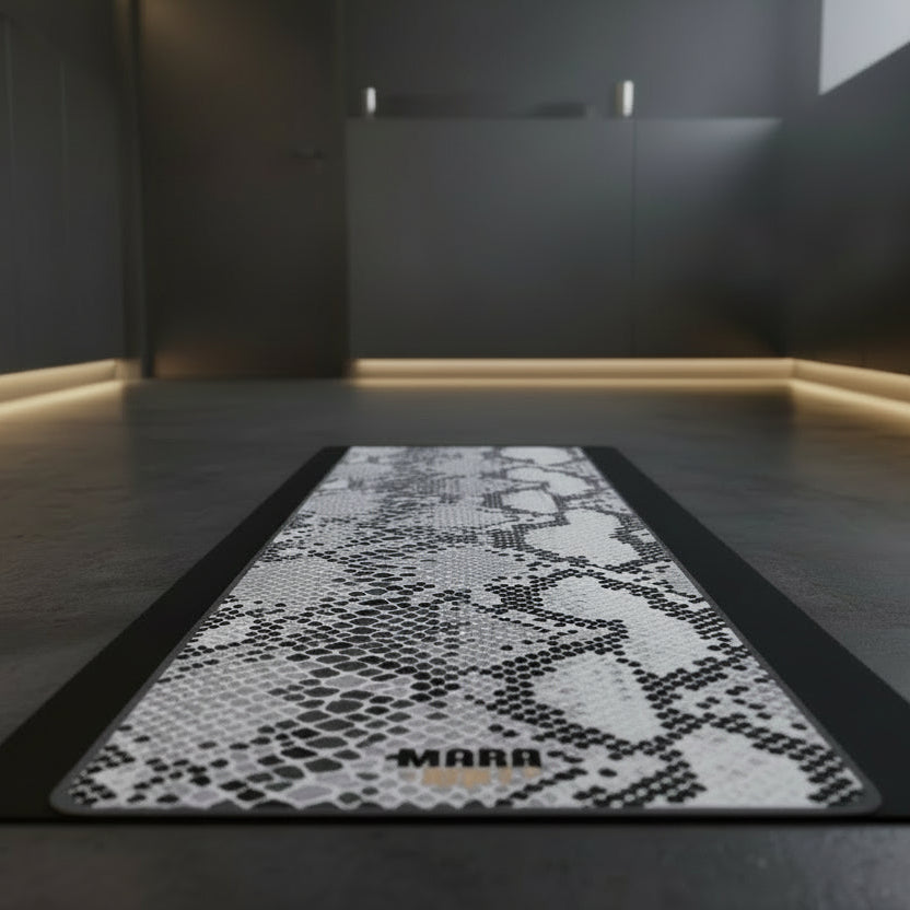 Snakeskin-patterned mat with 'MARR' branding on a dark floor.