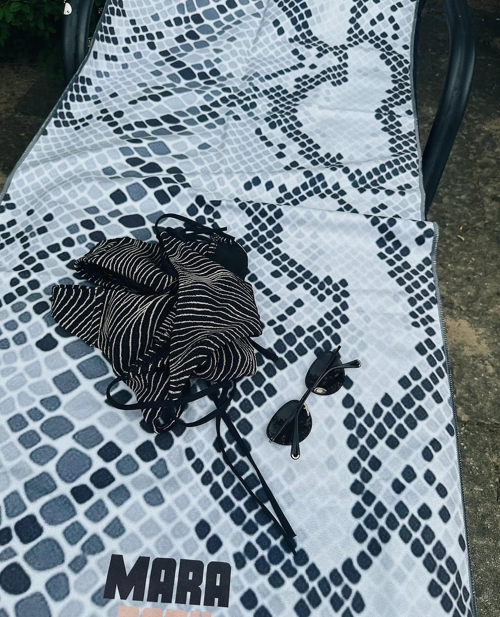 microfibre yoga towel for hot yoga layered of a sunbed with swim suite and sunglasses.