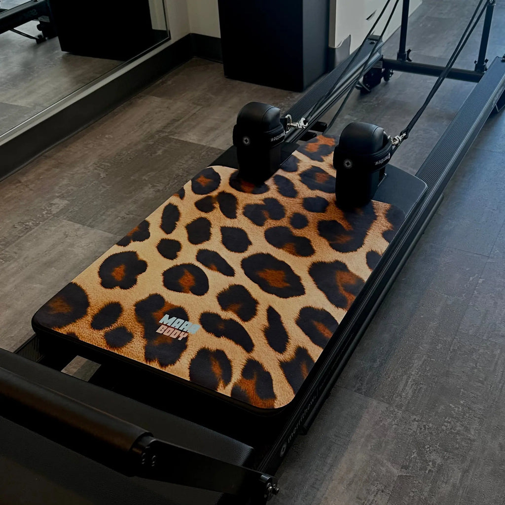 leopard print reformer mat on top of black pilates reformer machine