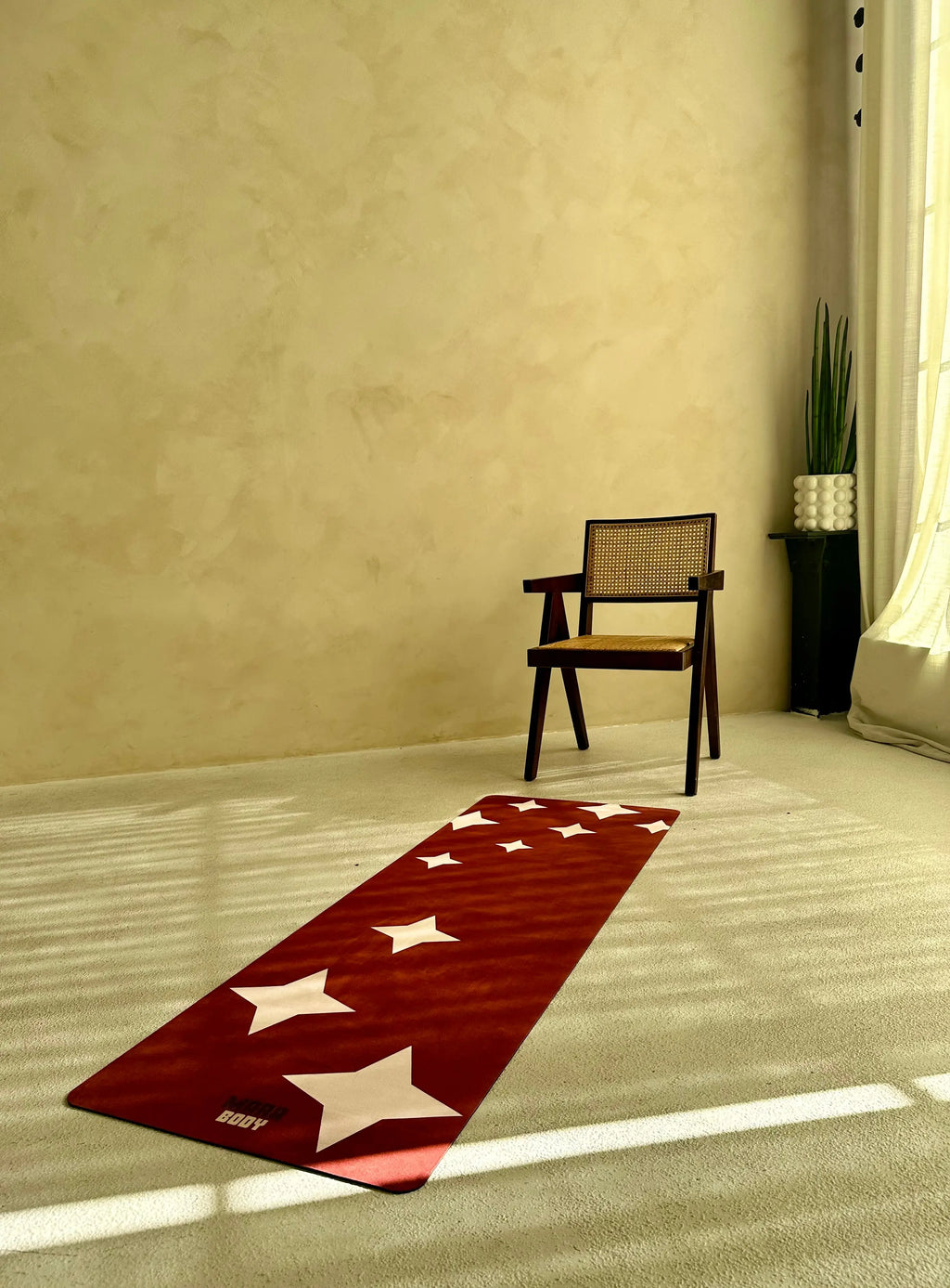 Yoga mat with star patterns on a floor next to a chair in a room.